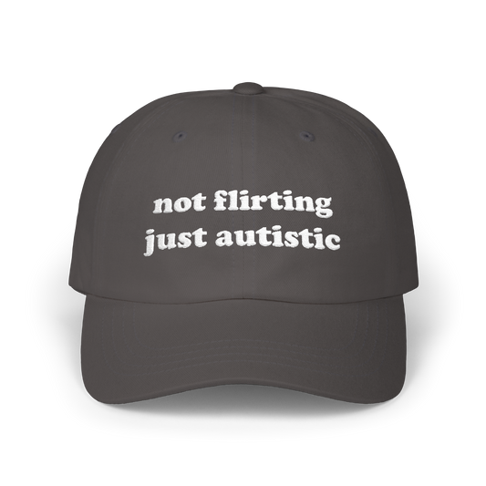 Dark grey dad hat with "not flirting just autistic" embroidered in white on the front panel