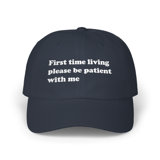 Navy dad hat with "First time living please be patient with me" embroidered in white on the front panel