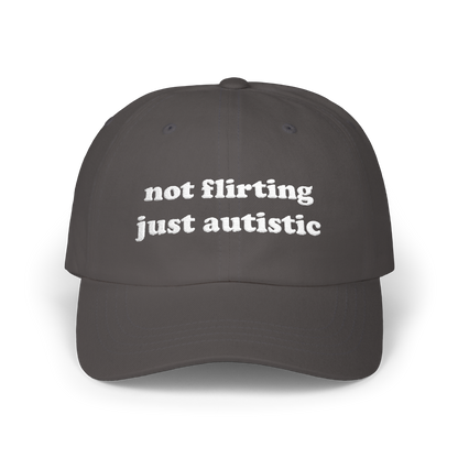 Dark grey dad hat with "not flirting just autistic" embroidered in white on the front panel